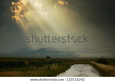 Scenery with sun rays after rain at sunset