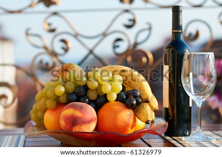 Fresh summer fruits and bottle of wine in a sea-side veranda