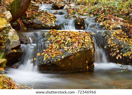 Autumn scenery with waterfall and yellow autumn forest leafs