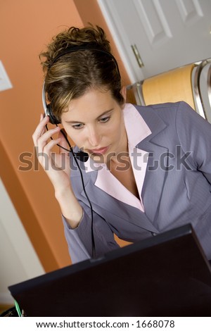 Model Release 352  Woman in early 20s working on computer and talking on headset telephone at home