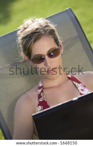 Model Release 352  Woman in mid 20s sunbathing and working on a laptop computer
