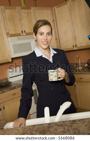 Model Release 357  Businesswoman in early 20s standing in the kitchen dresses in a business suit and holding a coffee cup