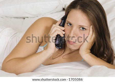 Caucasian woman in early 20\'s laying in bed talking on the phone