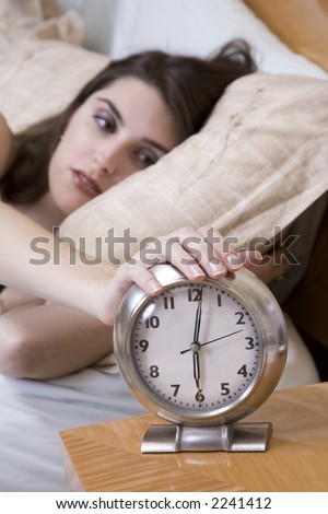 Woman in early waking up to an alarm clock