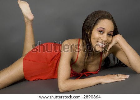 African American woman posing on gray background in red lingerie