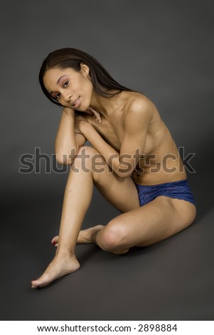 African American woman posing on gray background in blue panties