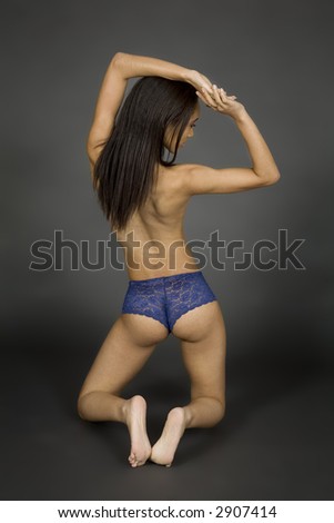 African American woman posing on gray background in blue panties