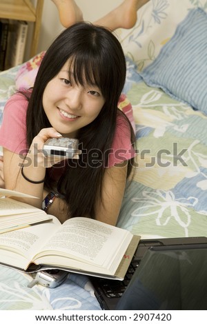 Asian American teen watching television while doing homework