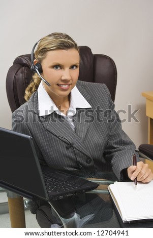 Caucasian businesswoman in her early 30s setting at a desk going over a  day planner