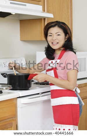 Beautiful Asian woman cooking a large pot of stew on the stove