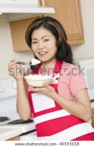 Beautiful Asian woman eating ice cream with in the kitchen