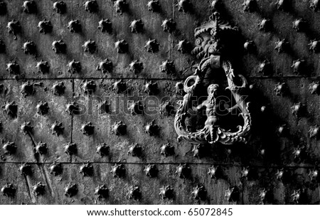 Ancient metal door with knocker door and spike. Black and white. Ancient door knocker