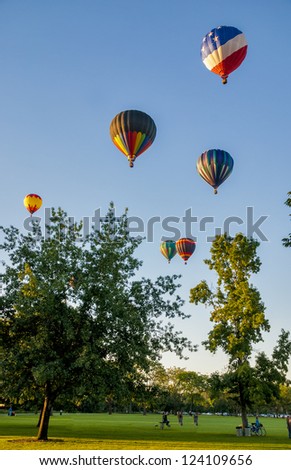 Many balloons lift off in a city