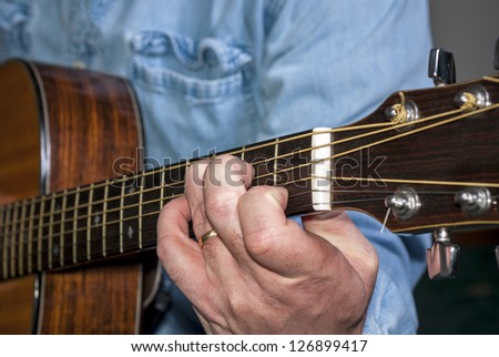 Music is played on an Musician plays a C cord on an Acoustic guitar