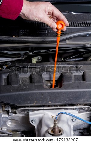 Pulling dipstick out of a car engine to check the oil