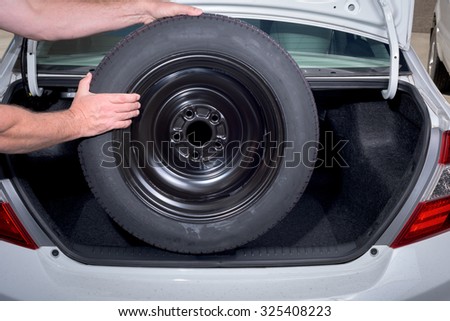 Removing a spare tire from the trunk of a car