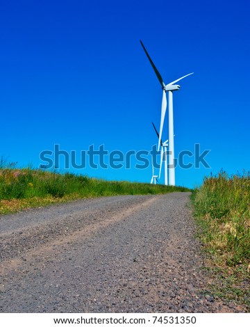 These Wind Generators are collecting electricity from the wind along a dirt road