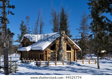 Winter in the Idaho mountains covers this log cabin with snow.