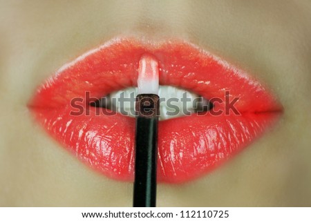 Woman make her lips with red lip  gloss