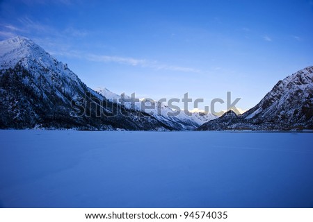 clean lake sunset covered by heavy snow in tibet with blue sky and white cloud