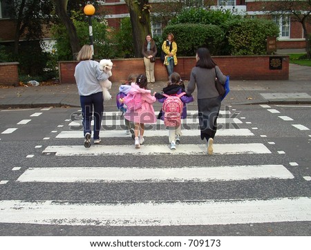 Young family crossing the famous abbey road crossing in londons west end.  Beatles done it years ago . but same crossing.