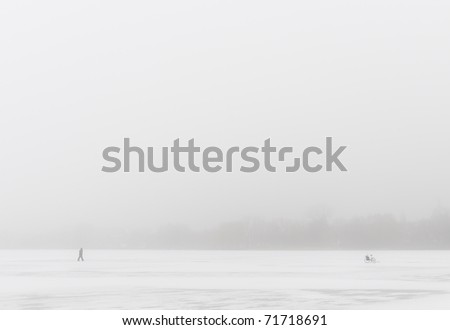 Man going to his bicycle in the deep fog, on frozen lake.