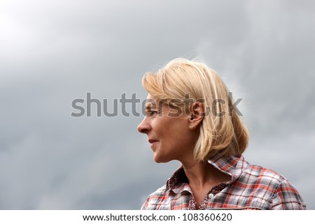 A mature woman head shot with stormy sky background