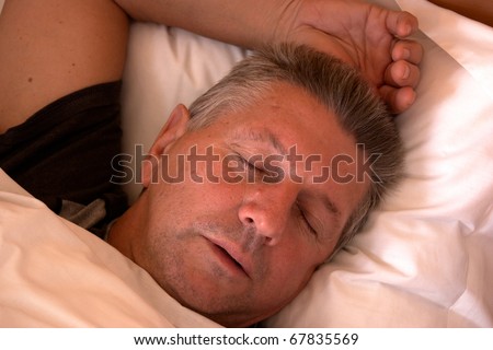 Mature man clothed and asleep in bed