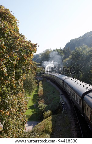 A steam train traveling on the tracks with steam rising in the air