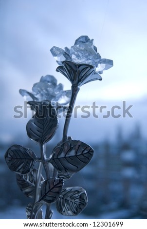 Bluish glass and metal rose arrangement against a winter backdrop