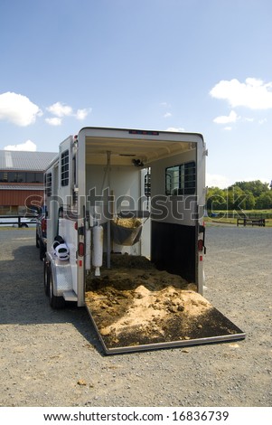 Horse trailer parked in parking lot and filled with hay
