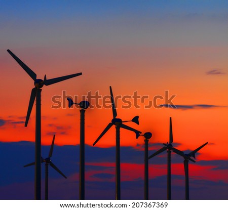Clean energy wind turbine silhouettes are working at twilight.