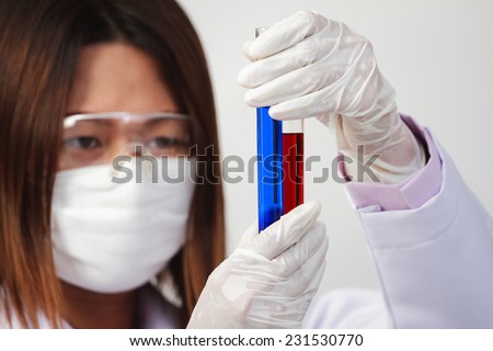 Investigator checking test tubes, Woman wears protective goggles.