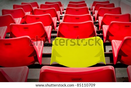 A yellow vip and many red  seat in football stadium