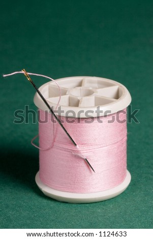 A self threading needle in a bobbin of pink thread