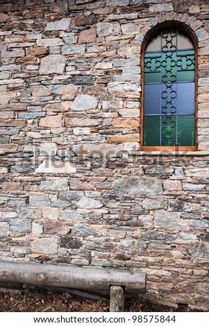 Old refurbished window on church wall with wood bench