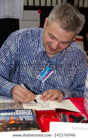 WARSAW, POLAND - MAY 18: Marcin Bruczkowski signs his book on the Fourth Book Fair held at the National Stadium on May 18, 2013 in Warsaw