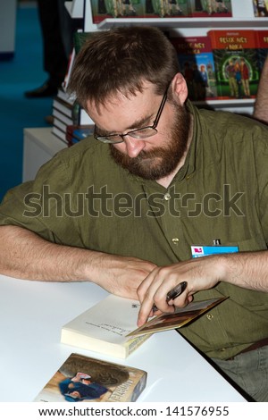 WARSAW, POLAND - MAY 18: Andrzej Pilipiuk signs his book on the Fourth Book Fair held at the National Stadium on May 18, 2013 in Warsaw