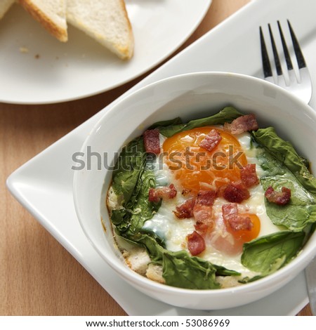 Delicious baked eggs and spinach with lardon, cheese and toast
