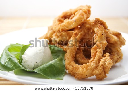 deep fat fried breaded calamari rings with a dollop of cream cheese on fresh basil leaves