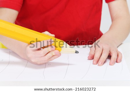 Little boy writing with a big pen