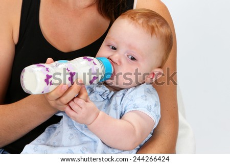 A mother feeding her baby girl a bottle of milk