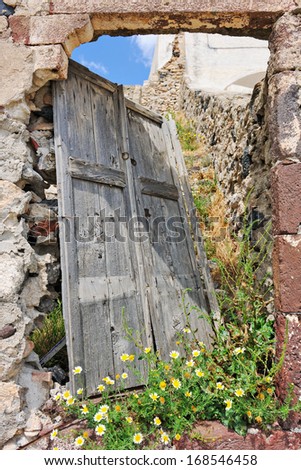 Broken door of abandoned house and overgrown plants in Pyrgos, Santorini, Cyclades, Greece