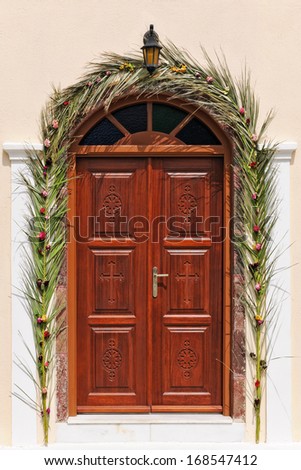 Church door decorated with floral wedding garland in Santorini, Cyclades, Greece