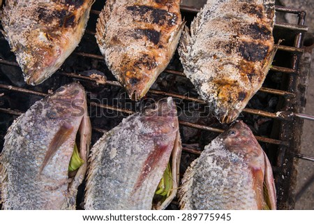 fresh delicious grilled fish, tilapia, nile fish with salt. dark burn skin with charcoal outdoor for sale on street market in THAILAND