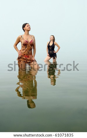 Two women in cocktail dress staying in lake