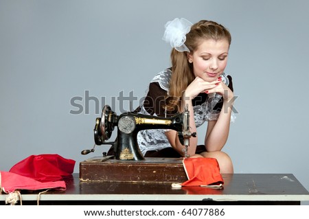 Studio shot of a girl stylized like a Soviet Union student sewing on a machine