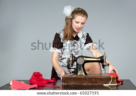 Studio shot of a girl stylized like a Soviet Union student sewing on a machine