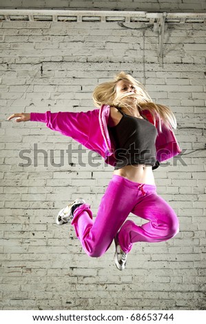 Shot of modern dancer jump against brick wall.