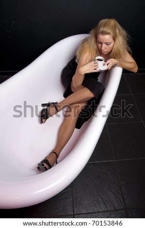 Business woman with cup of coffee sitting in a bath